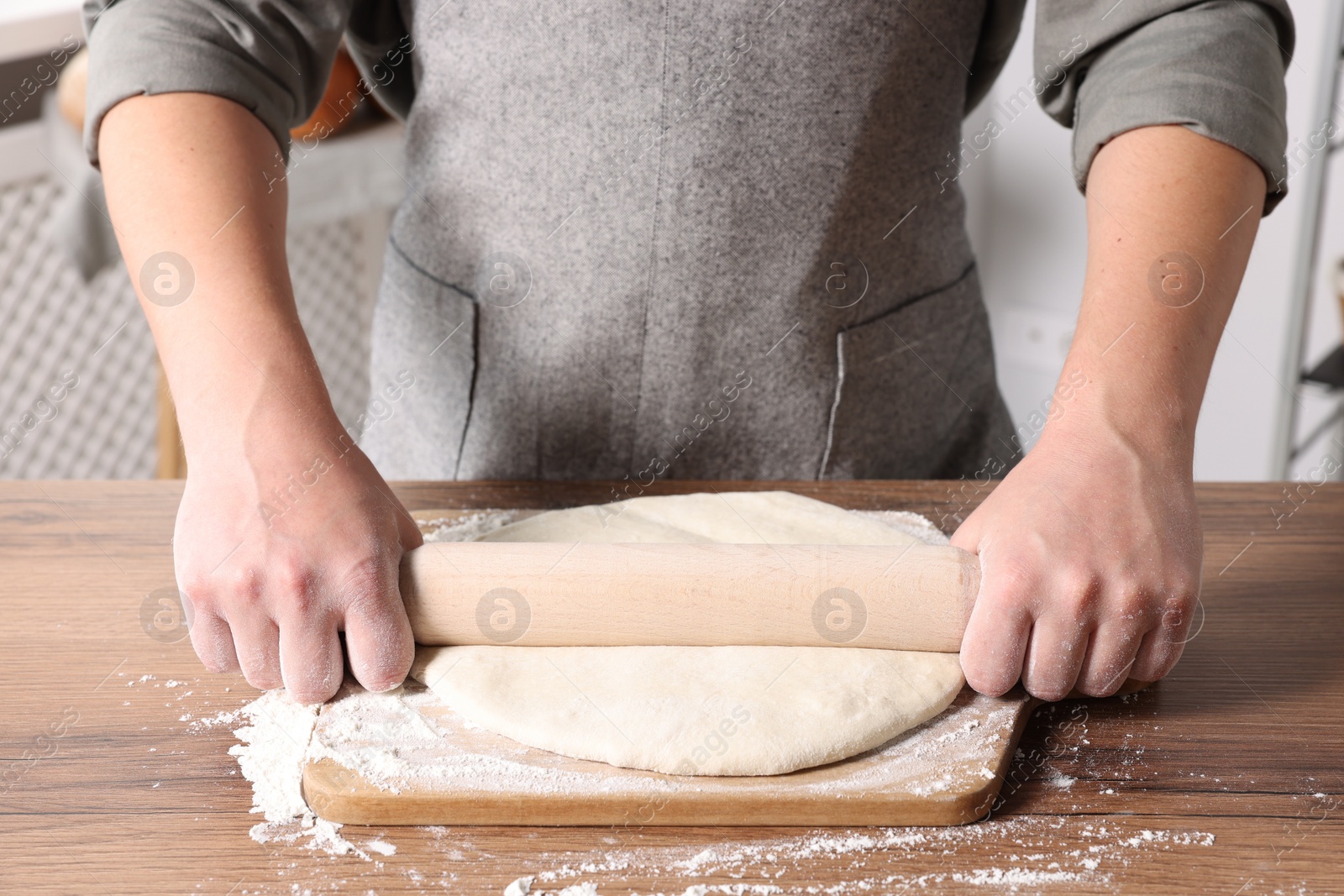 Photo of Man rolling dough at table in kitchen, closeup