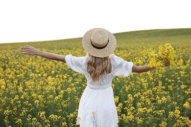 Young woman with straw hat in field on spring day, back view