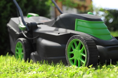 Photo of Lawn mower on green grass in garden, closeup