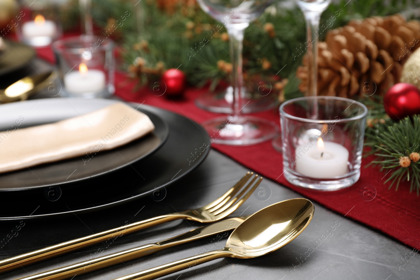 Photo of Christmas table setting with plates, cutlery, napkin and festive decor on grey background, closeup