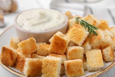 Delicious crispy croutons with rosemary and sauce on plate, closeup