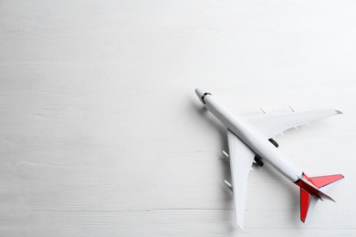 Photo of Toy airplane on white wooden background, top view. Space for text