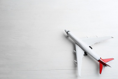 Toy airplane on white wooden background, top view. Space for text