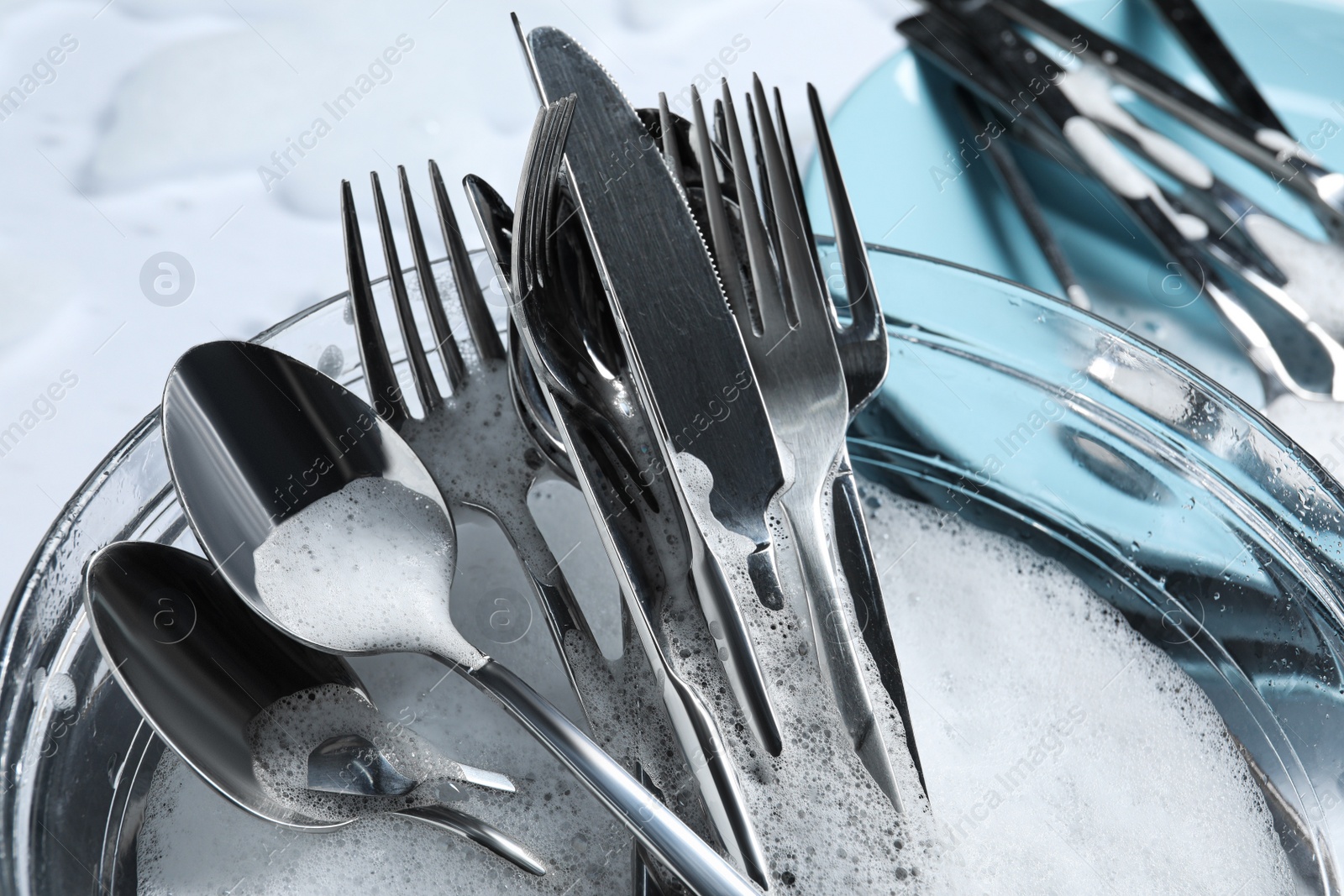 Photo of Glass bowl with silverware in foam, closeup