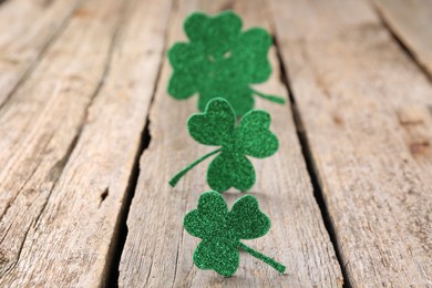 St. Patrick's day. Shiny decorative clover leaves on wooden table, selective focus