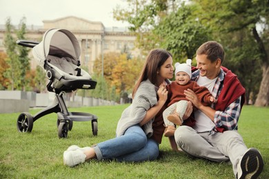 Photo of Happy parents with their adorable baby on green grass in park