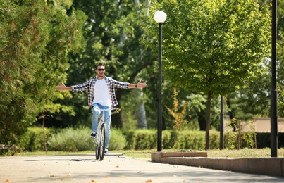 Photo of Handsome young hipster man riding bicycle in park