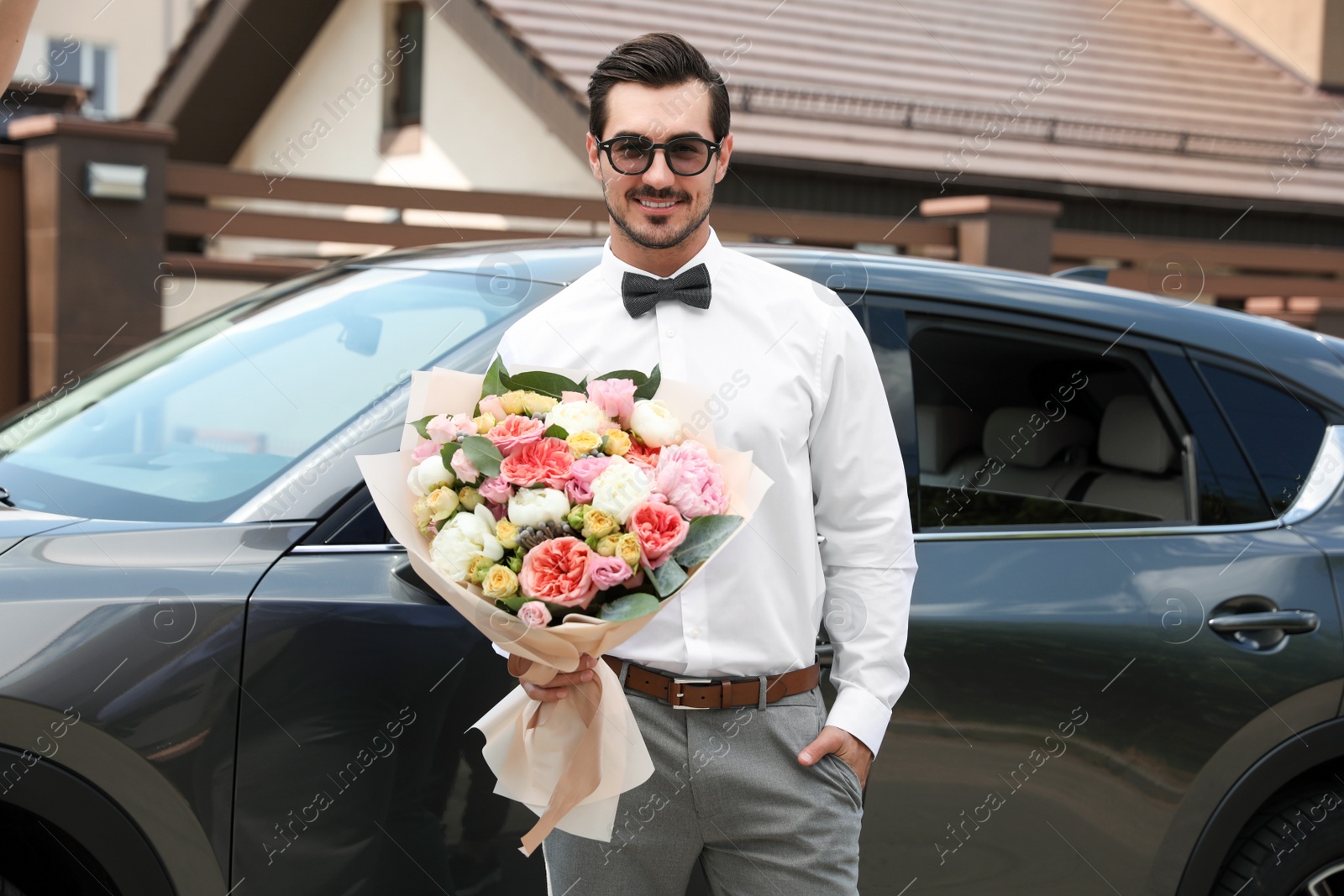 Photo of Young handsome man with beautiful flower bouquet near car outdoors