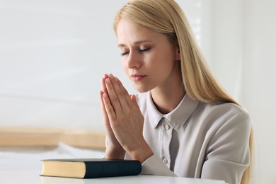 Photo of Religious young woman with Bible praying at home