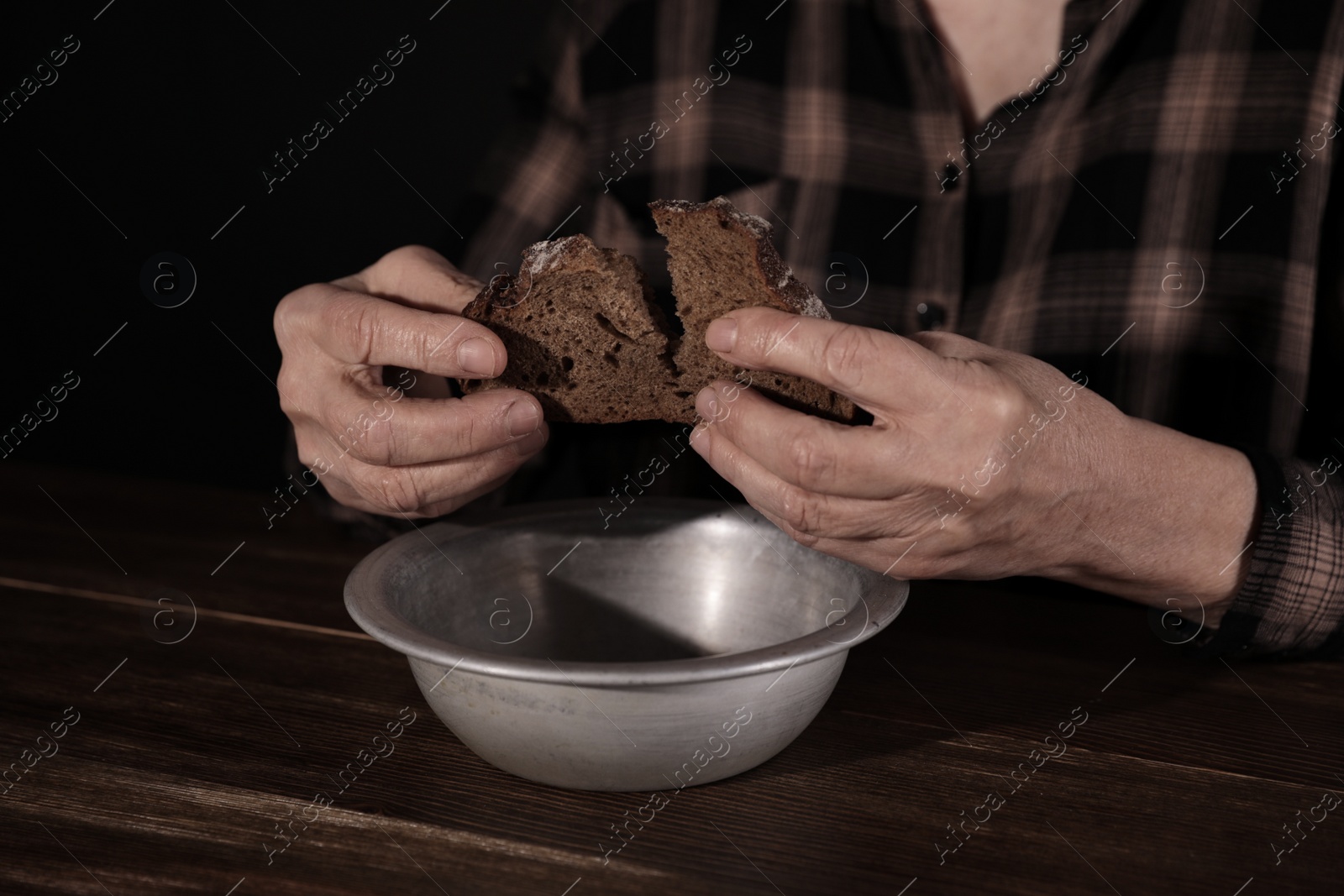 Photo of Poor mature woman with bread and bowl at table, closeup