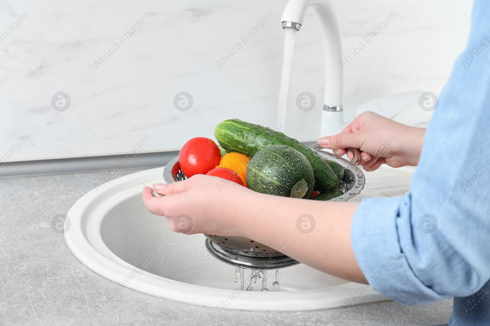 Photo of Woman washing fresh vegetables in colander under water, closeup