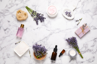 Photo of Frame of cosmetic products and lavender flowers on white marble table, flat lay. Space for text