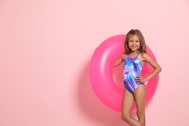 Cute little girl with bright inflatable ring on color background