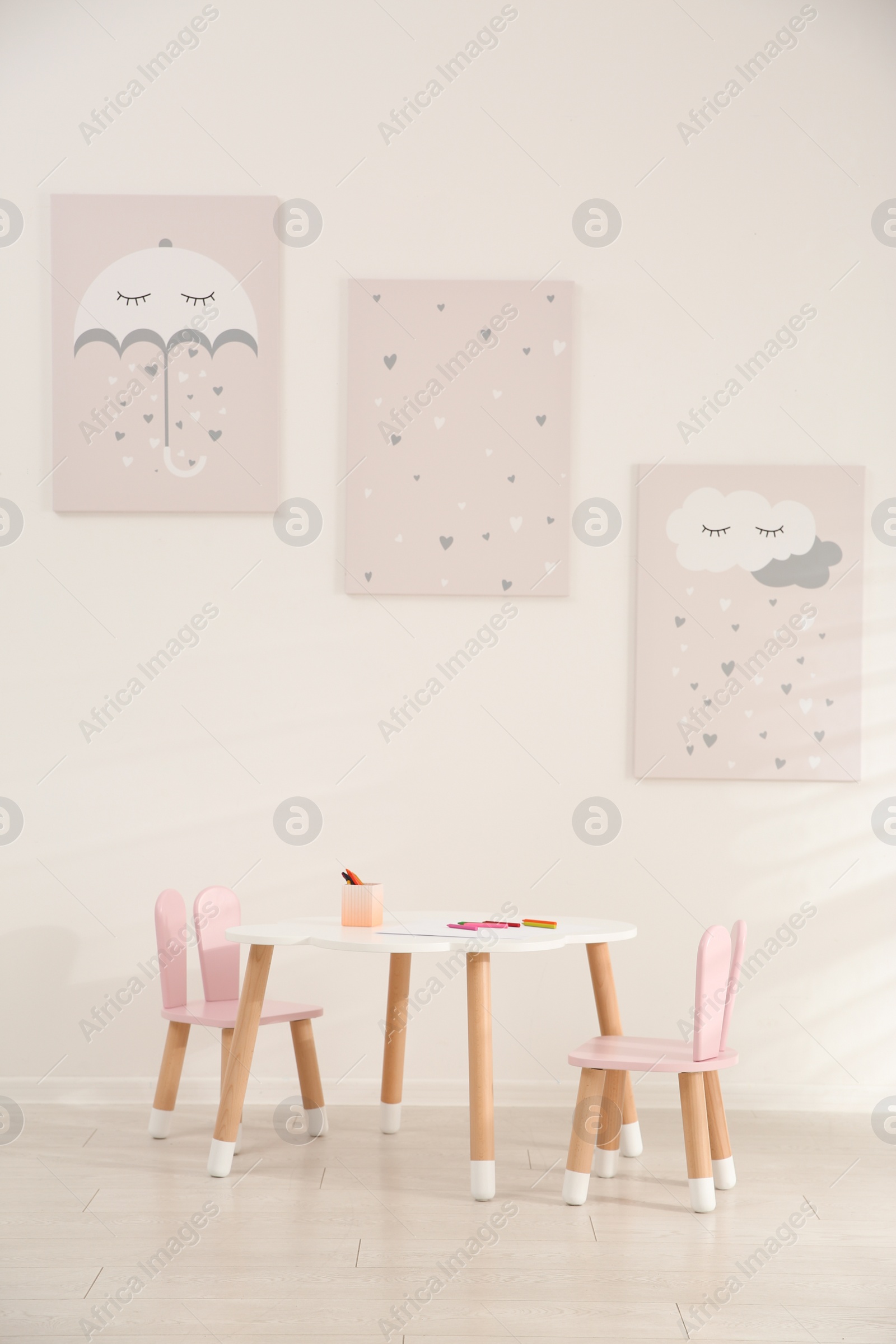 Photo of Little table and chairs with bunny ears in children's room. Interior design