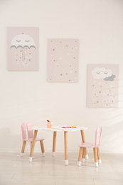 Photo of Little table and chairs with bunny ears in children's room. Interior design