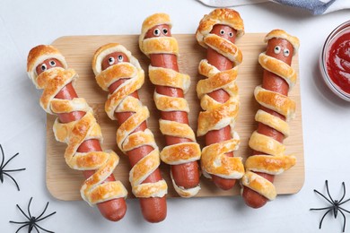 Photo of Cute sausage mummies served on white table, flat lay. Halloween party food