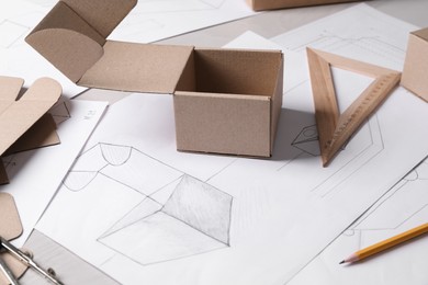 Photo of Creating packaging design. Drawings, boxes and stationery on table, closeup