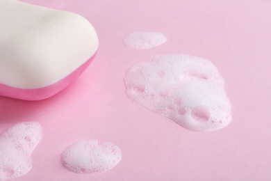 Soap bar and foam on color background, closeup view