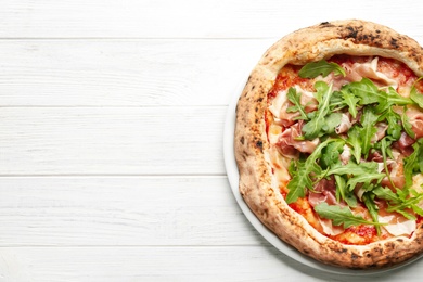 Photo of Tasty pizza with meat and arugula on white wooden table, top view. Space for text