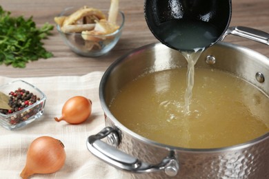 Photo of Delicious homemade bone broth and ingredients on wooden table, closeup