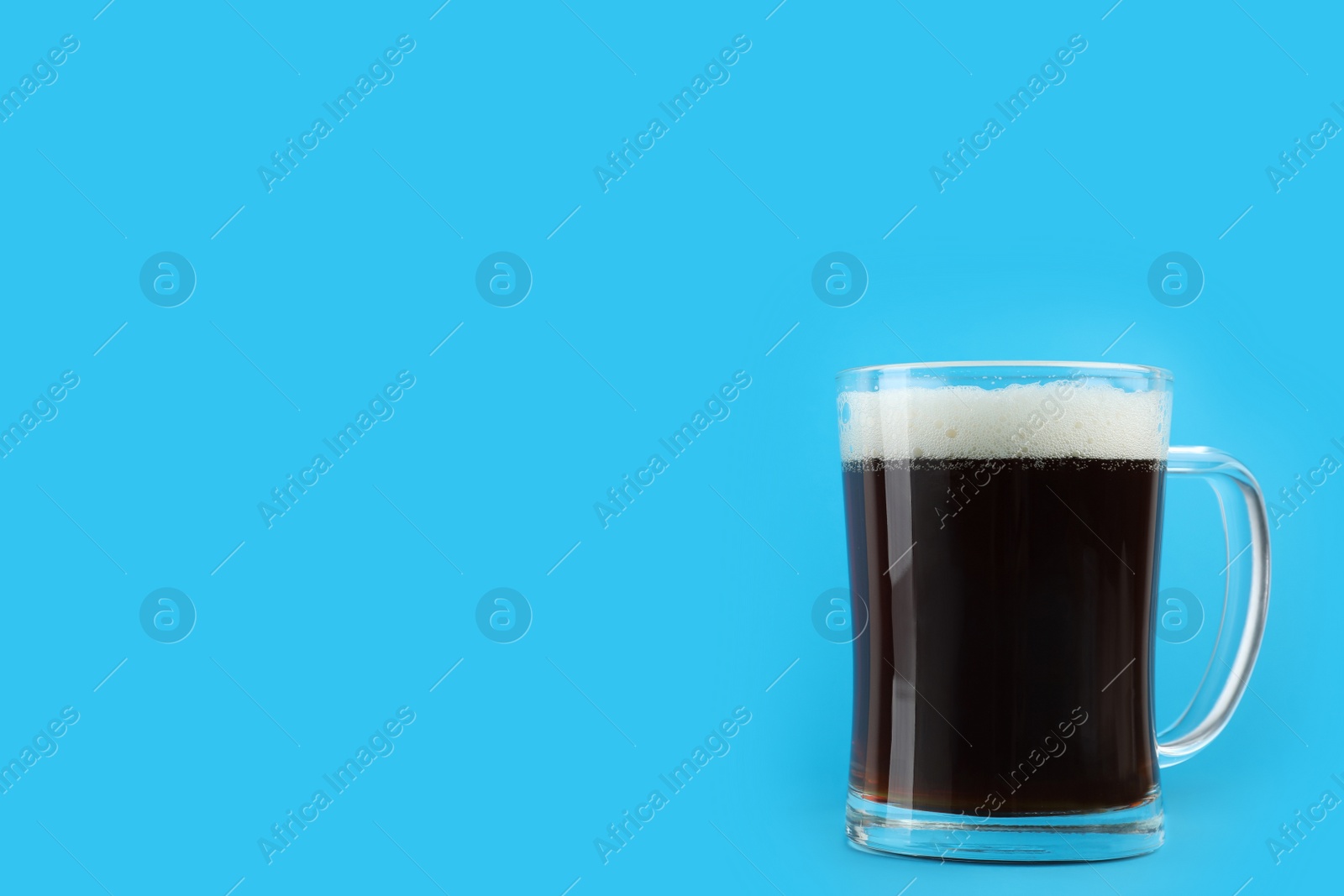 Photo of Delicious homemade kvass in glass mug on light blue background. Space for text