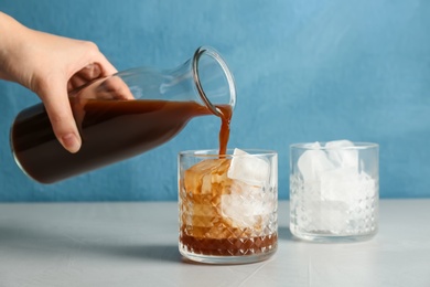 Photo of Woman pouring cold brew coffee into glass on table