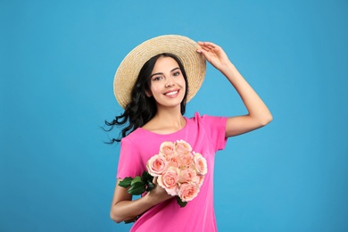 Portrait of smiling woman with beautiful bouquet on light blue background