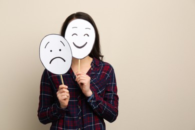 Photo of Woman with sad and happy paper faces on beige background. Space for text