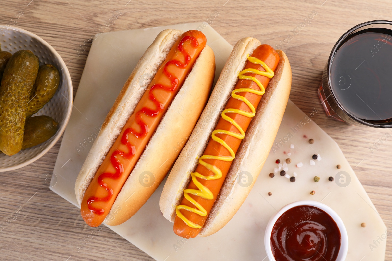 Photo of Tasty hot dogs with ketchup and mustard served on wooden table, flat lay