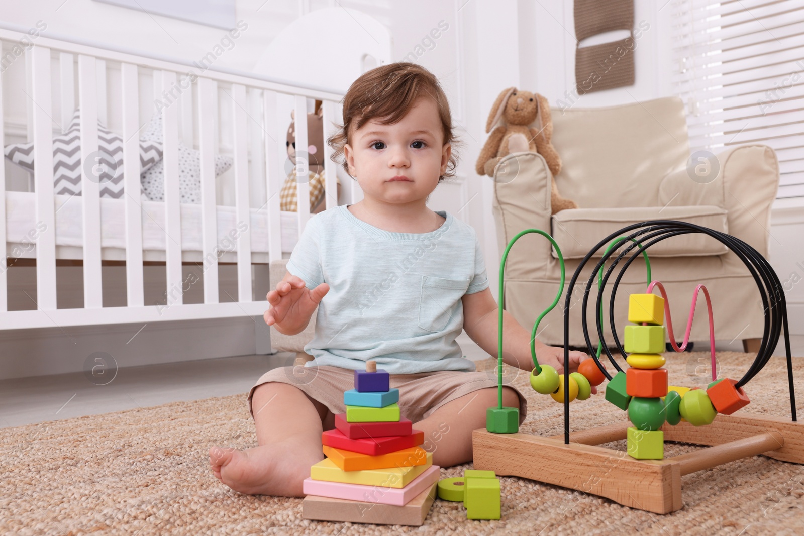 Photo of Cute little boy playing with toys on floor indoors