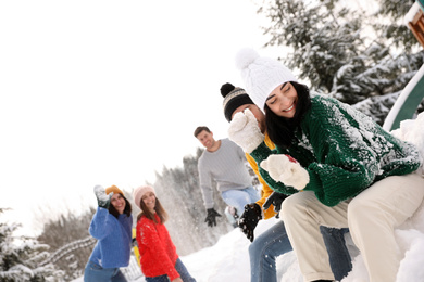 Group of friends playing snowballs outdoors. Winter vacation