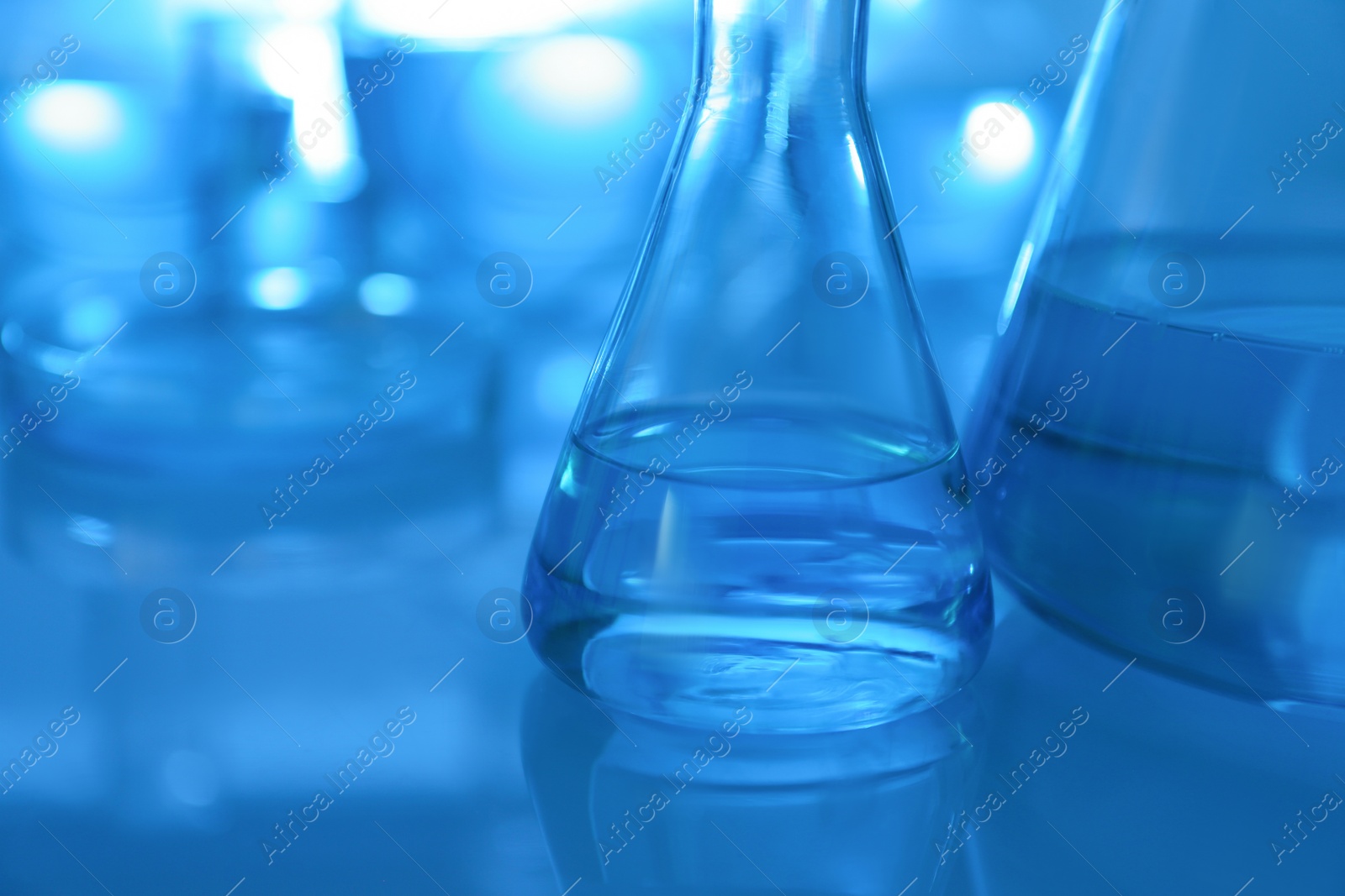 Photo of Laboratory glassware with liquid on table, closeup. Space for text