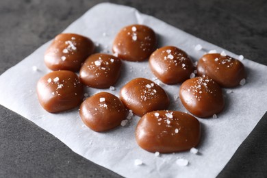 Photo of Tasty caramel candies and salt on grey table