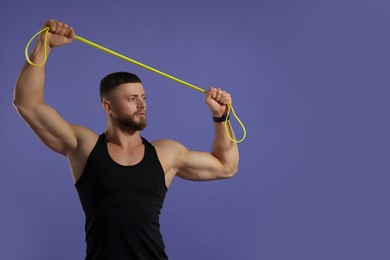 Photo of Muscular man exercising with elastic resistance band on purple background. Space for text