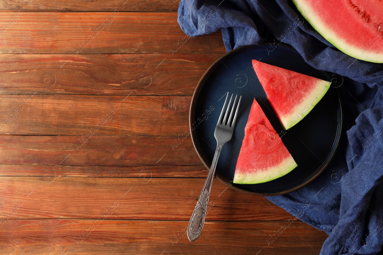 Photo of Sliced fresh juicy watermelon served on wooden table, flat lay. Space for text