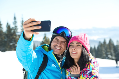 Photo of Happy couple taking selfie in mountains. Winter vacation