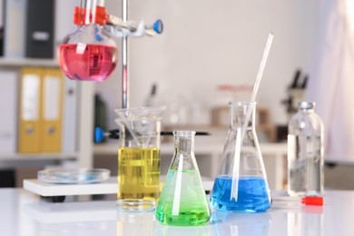 Photo of Laboratory analysis. Glassware with different liquids on white table indoors