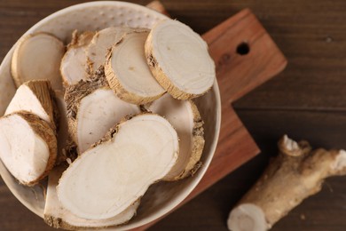 Photo of Cut horseradish roots on wooden table, top view