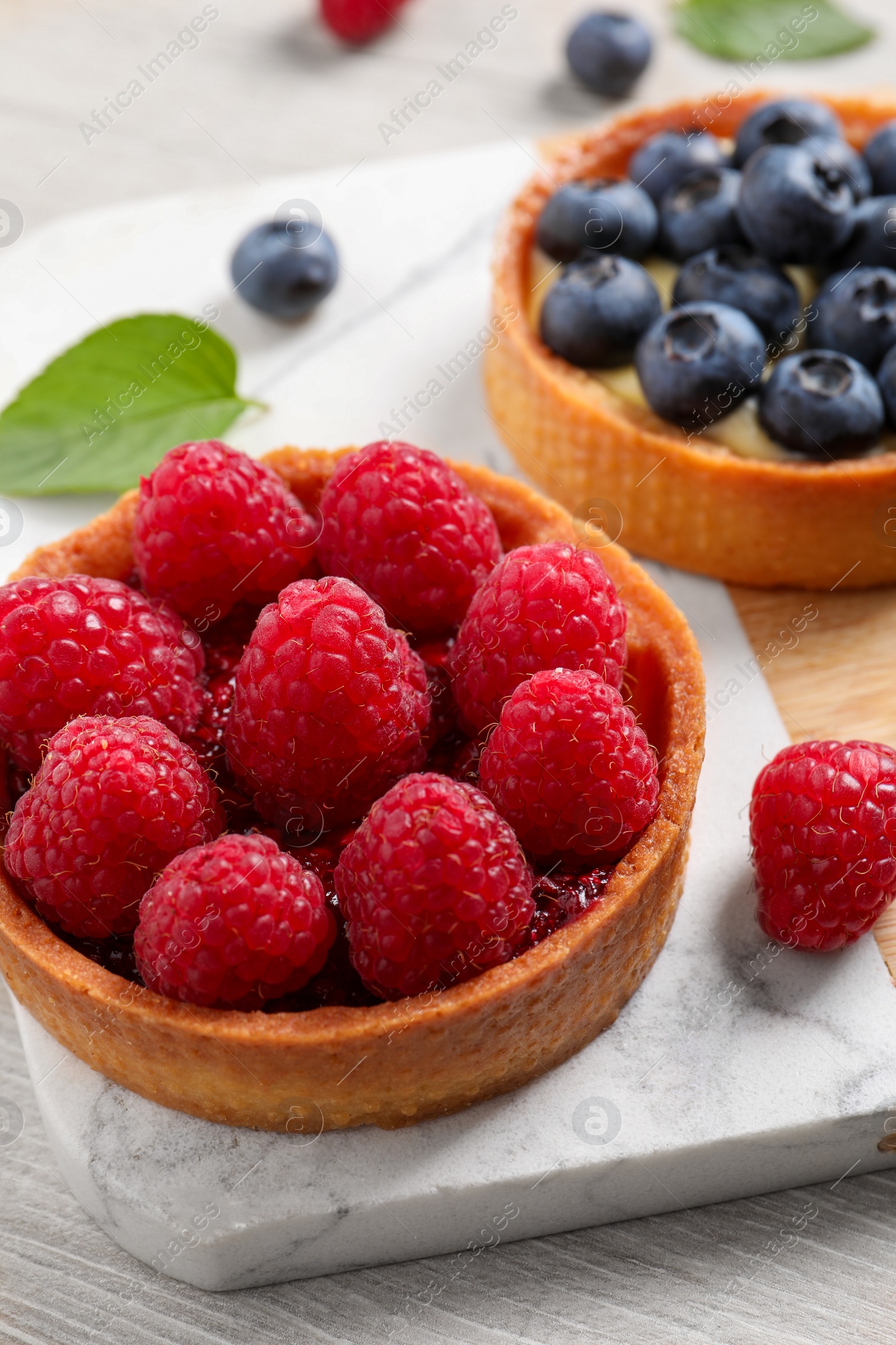 Photo of Tartlet with fresh raspberries on table, closeup. Delicious dessert