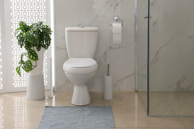 Photo of Toilet bowl near shower stall in modern bathroom