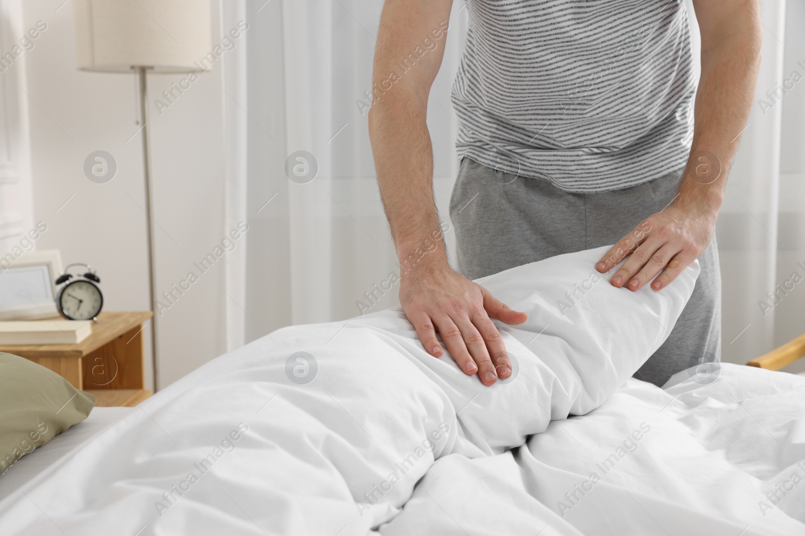 Photo of Man changing bed linens at home, closeup. Space for text