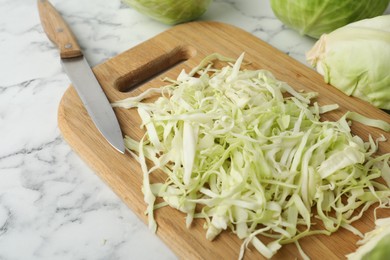 Photo of Chopped ripe cabbage on white marble table, closeup