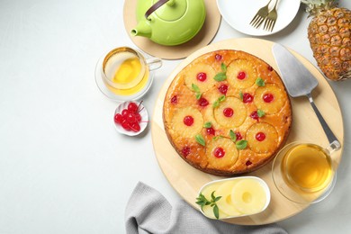 Tasty pineapple cake served with tea and ingredients on white table, flat lay. Space for text