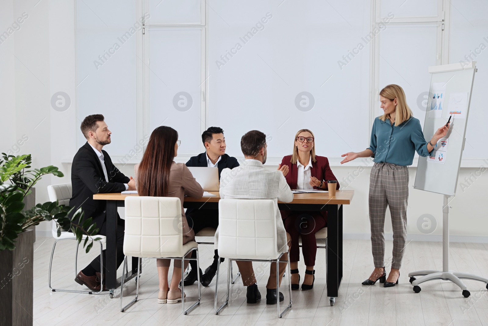 Photo of Businesswoman showing charts near flipchart on meeting in office