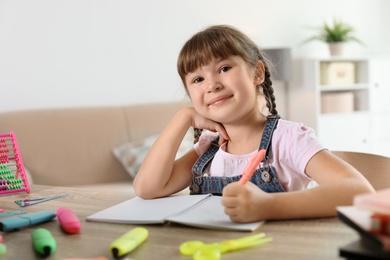 Photo of Little girl doing assignment at home. Stationery for school