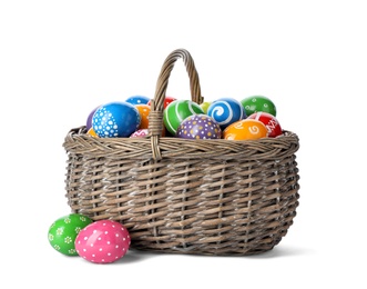 Photo of Decorated Easter eggs in wicker basket on white background