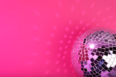 Photo of Shiny disco ball on pink background. Space for text