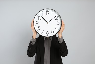 Photo of Businesswoman holding clock on light grey background. Time management