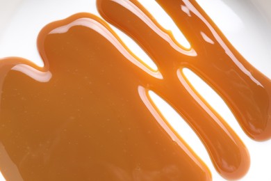 Photo of Delicious salted caramel sauce on white background, top view