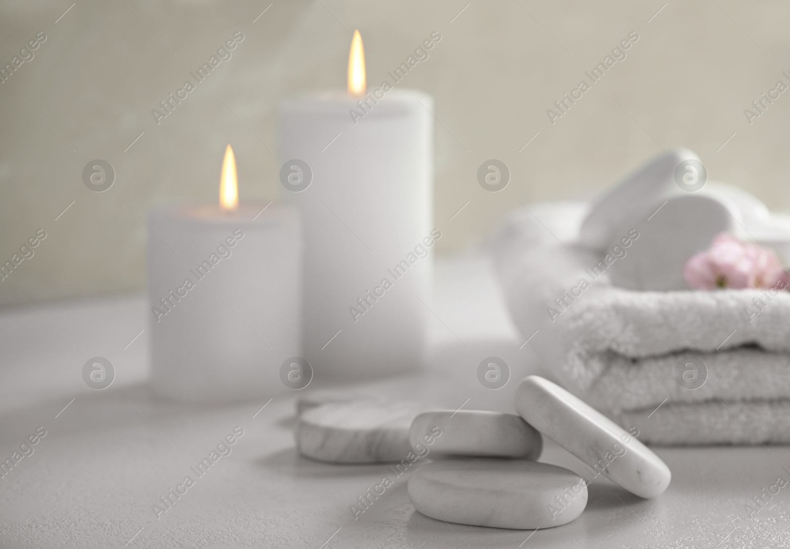 Photo of Spa stones, towel and candles on white table